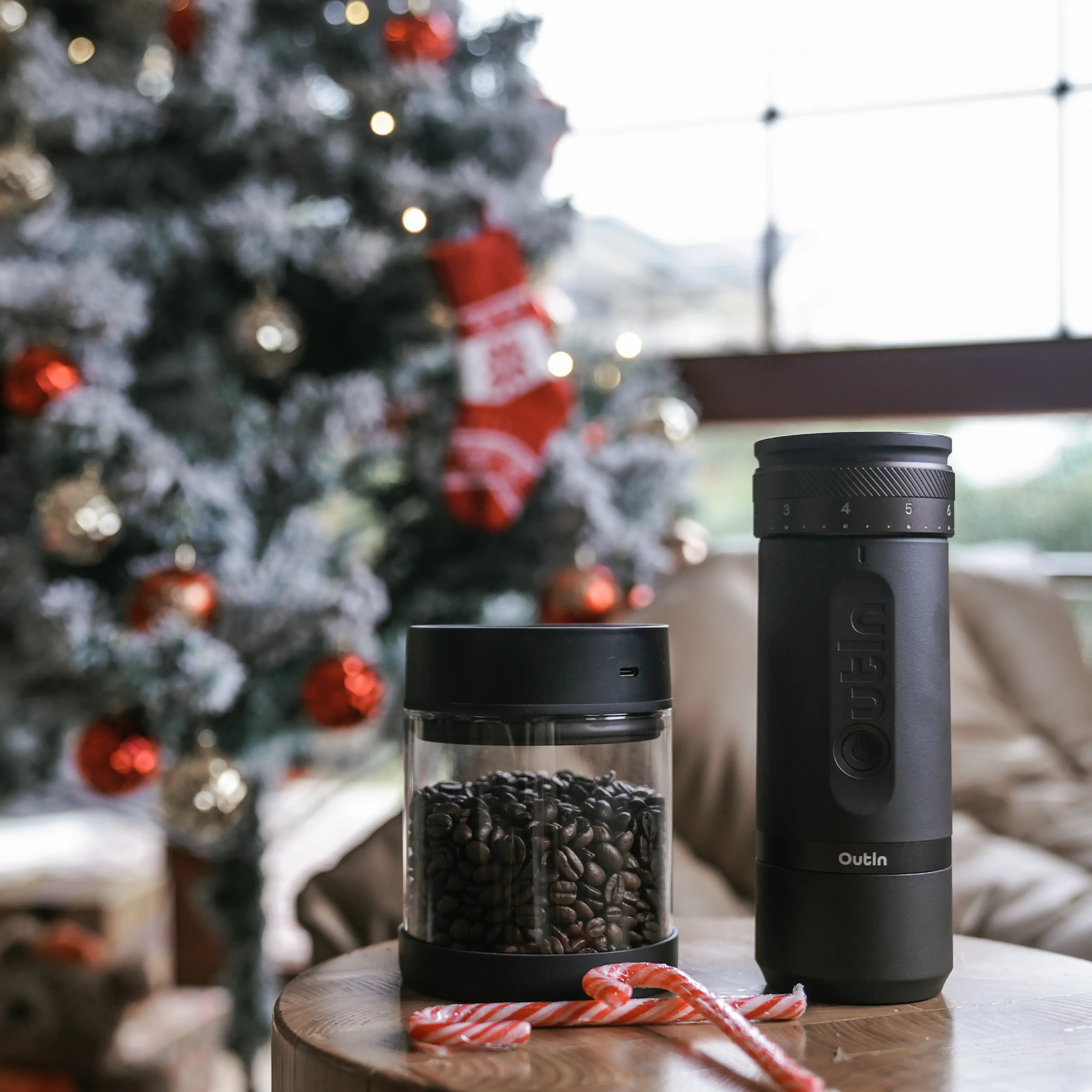 OutIn portable electric vacuum coffee canister and glass bean holder, festive holiday background.