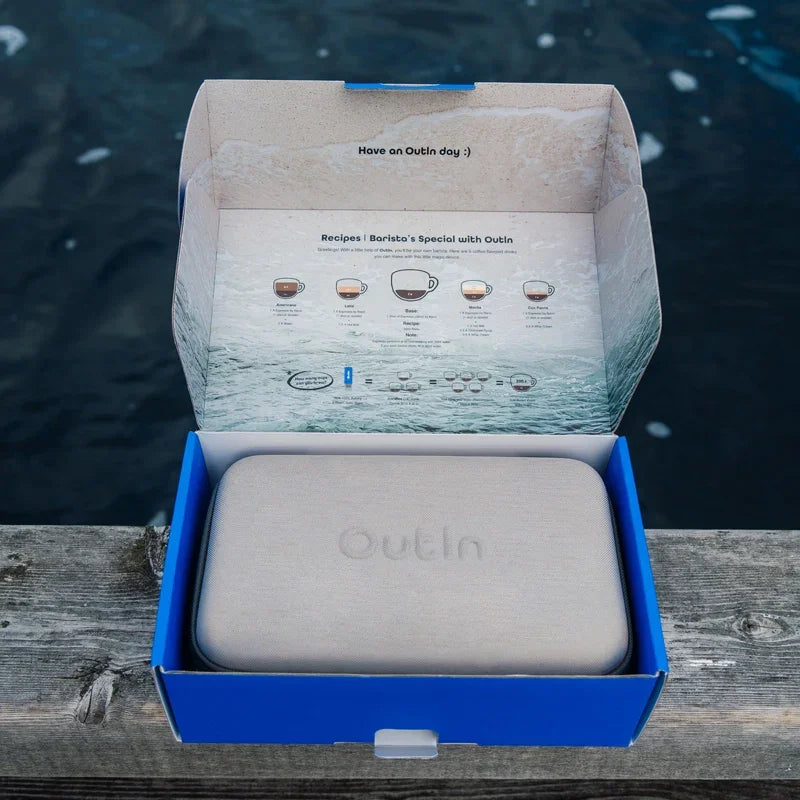 OutIn Nano portable espresso machine travel case in open retail packaging with brewing recipes inside lid.