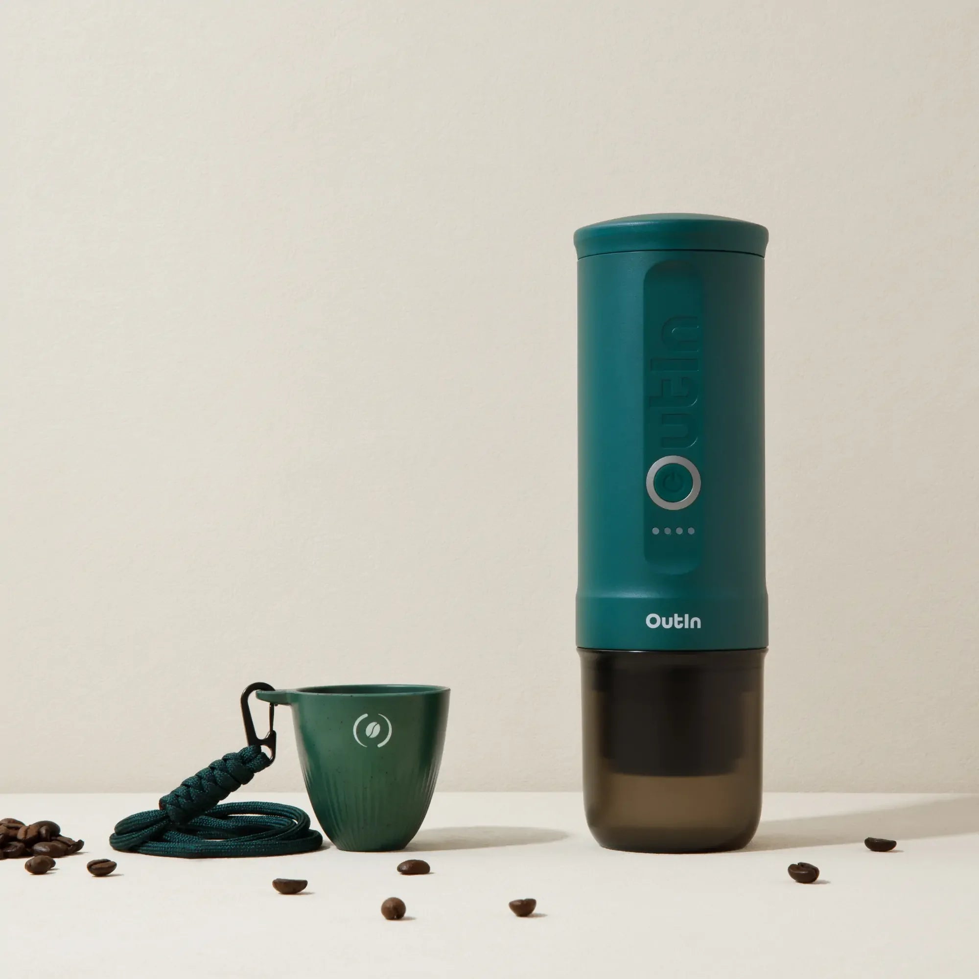 Dark green OutIn Rebrew espresso cup with lanyard and coffee bean logo, beside OutIn Nano machine (not included).