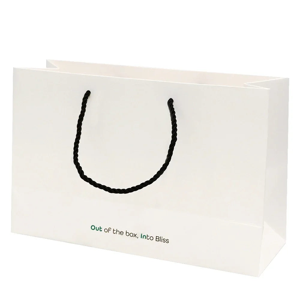 White gift bag for OutIn Nano Portable Espresso Machine, black rope handles, green 'Out of the box, Into Bliss' text.