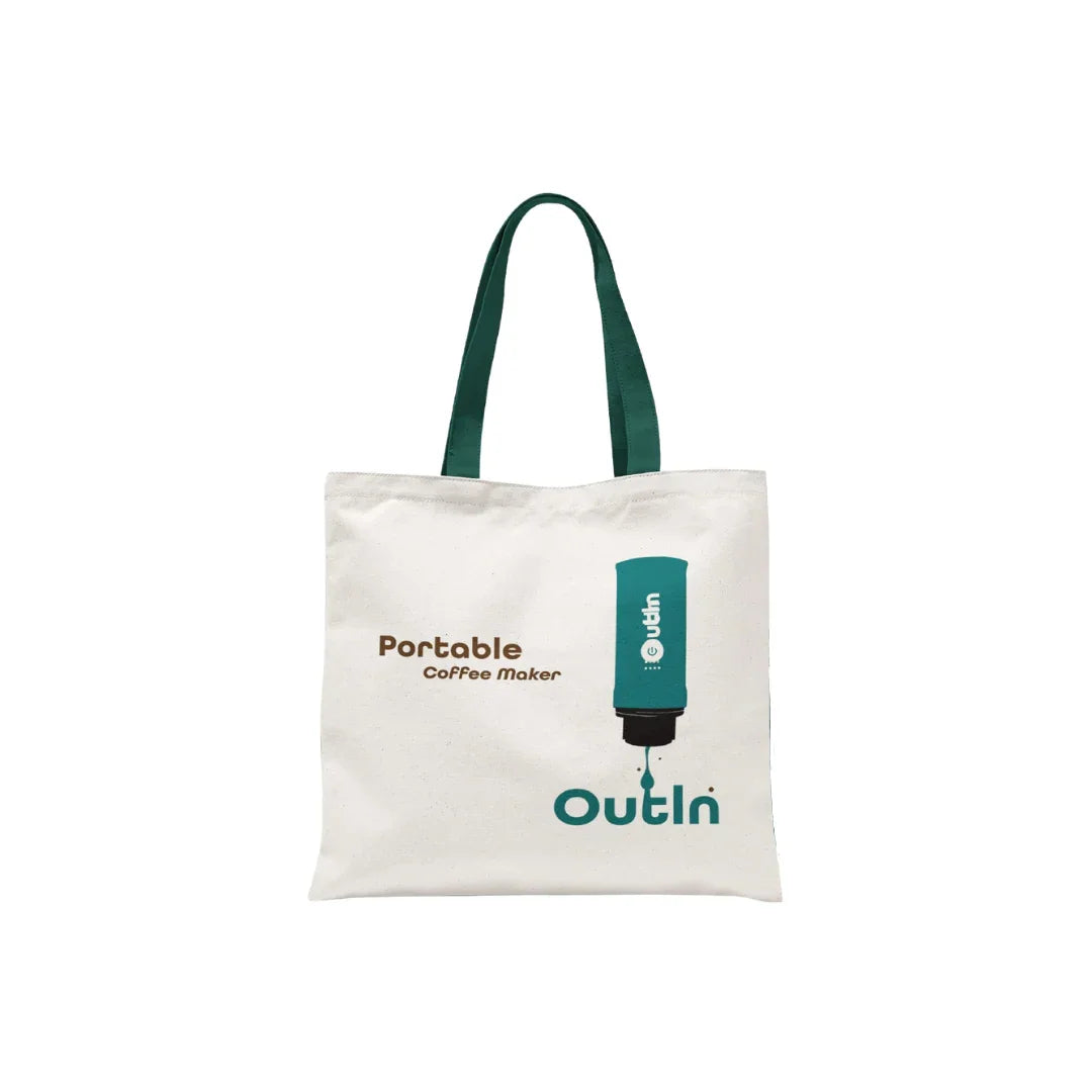 White Tyvek tote bag with dark green handles, printed "Portable Coffee Maker OutIn" and espresso machine graphic.