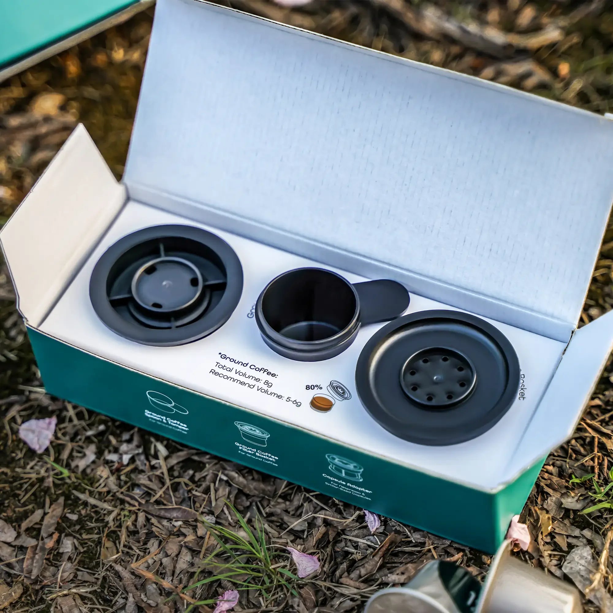 OutIn Nano portable espresso machine adapters kit with capsule adapter, ground coffee filter, and coffee spoon in open box.