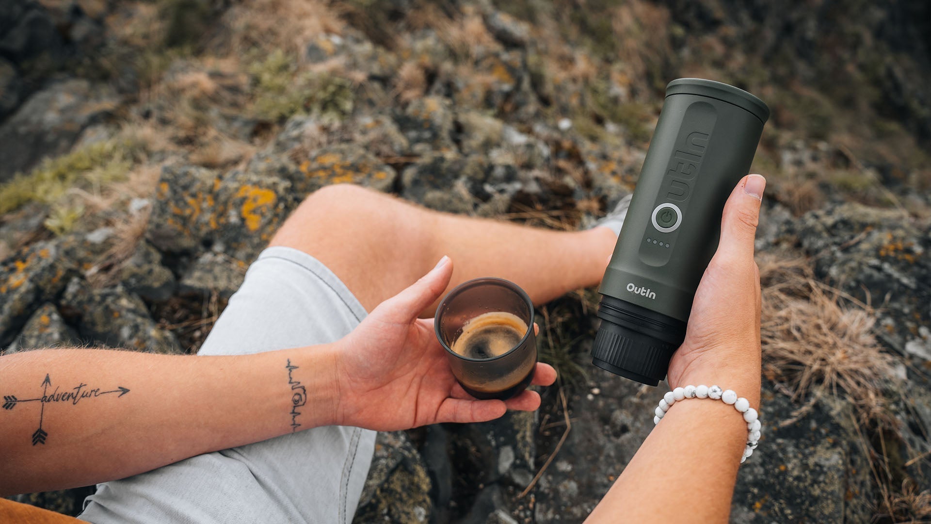 Enjoying espresso outdoors with portable espresso maker on rocky terrain