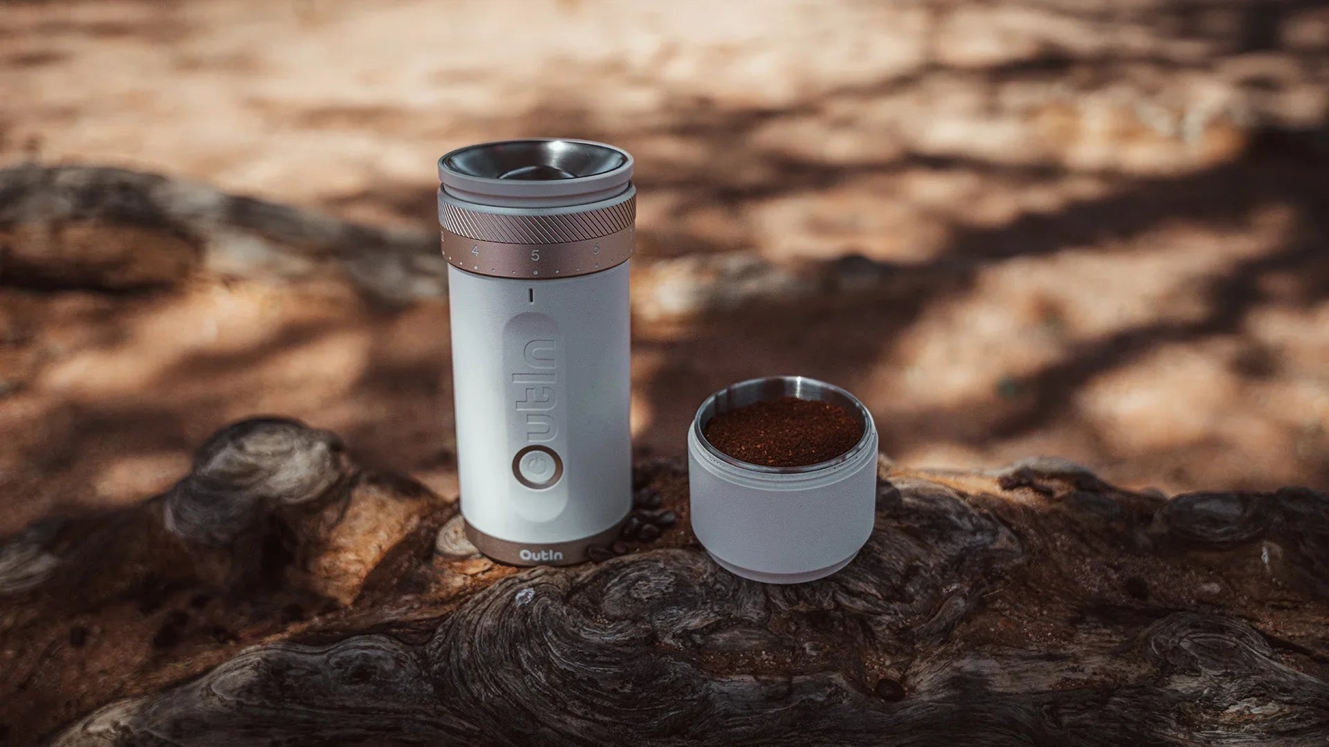 Hand pouring coffee beans into top of Outin manual grinder, demonstrating first step in grinding process with visible coarseness adjustment settings for precise control over grind size