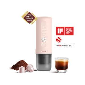 Rose Quartz portable espresso machine with coffee grounds, capsules, and award badges.