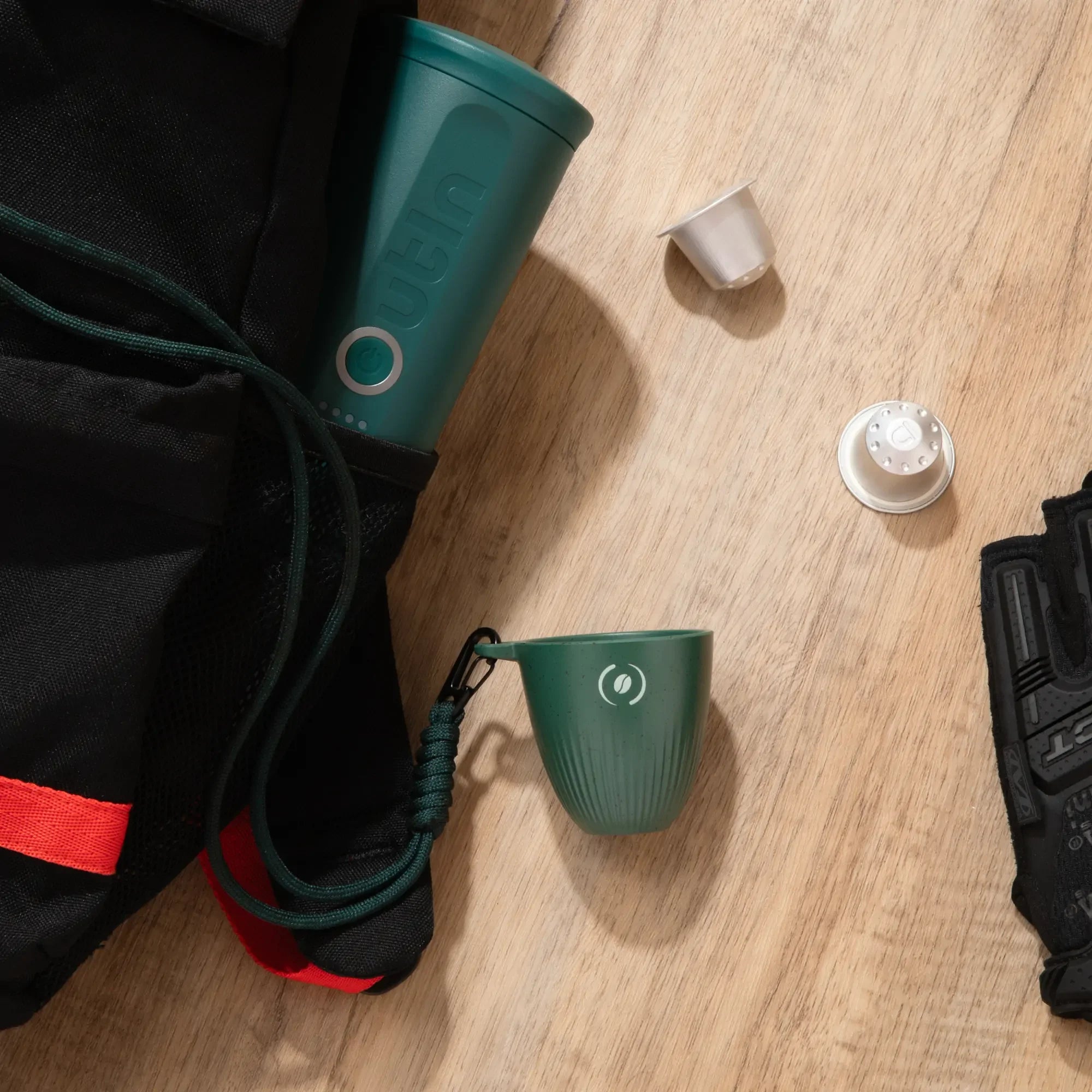 OutIn Rebrew dark green ribbed espresso cup with lanyard, shown with portable espresso maker for on-the-go coffee.