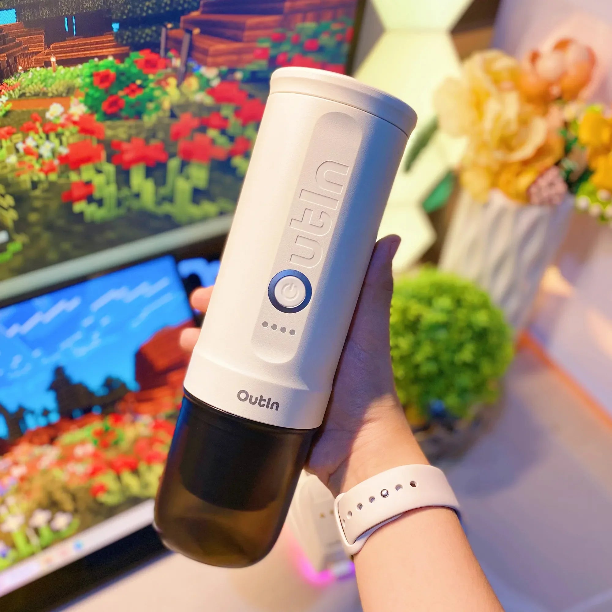 Pearl white OutIn Nano portable espresso machine held in hand, featuring blue power button and indicator lights.