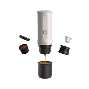 Pearl white Nano espresso machine brewing with crema, shows ground coffee and capsule parts.
