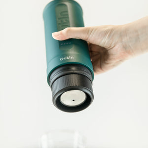 Teal OutIn Nano portable espresso machine brewing double espresso with its 16-18g basket attached.