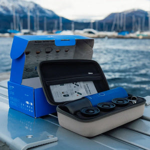 Ocean blue Nano portable espresso machine set with travel case and accessories by the water.
