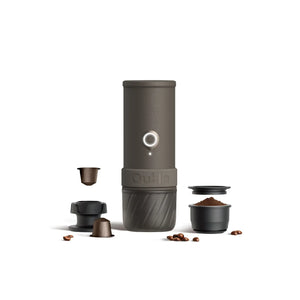 Dark gray OutIn portable espresso machine with coffee pods, grounds, tamper, and beans. Shows product and components.