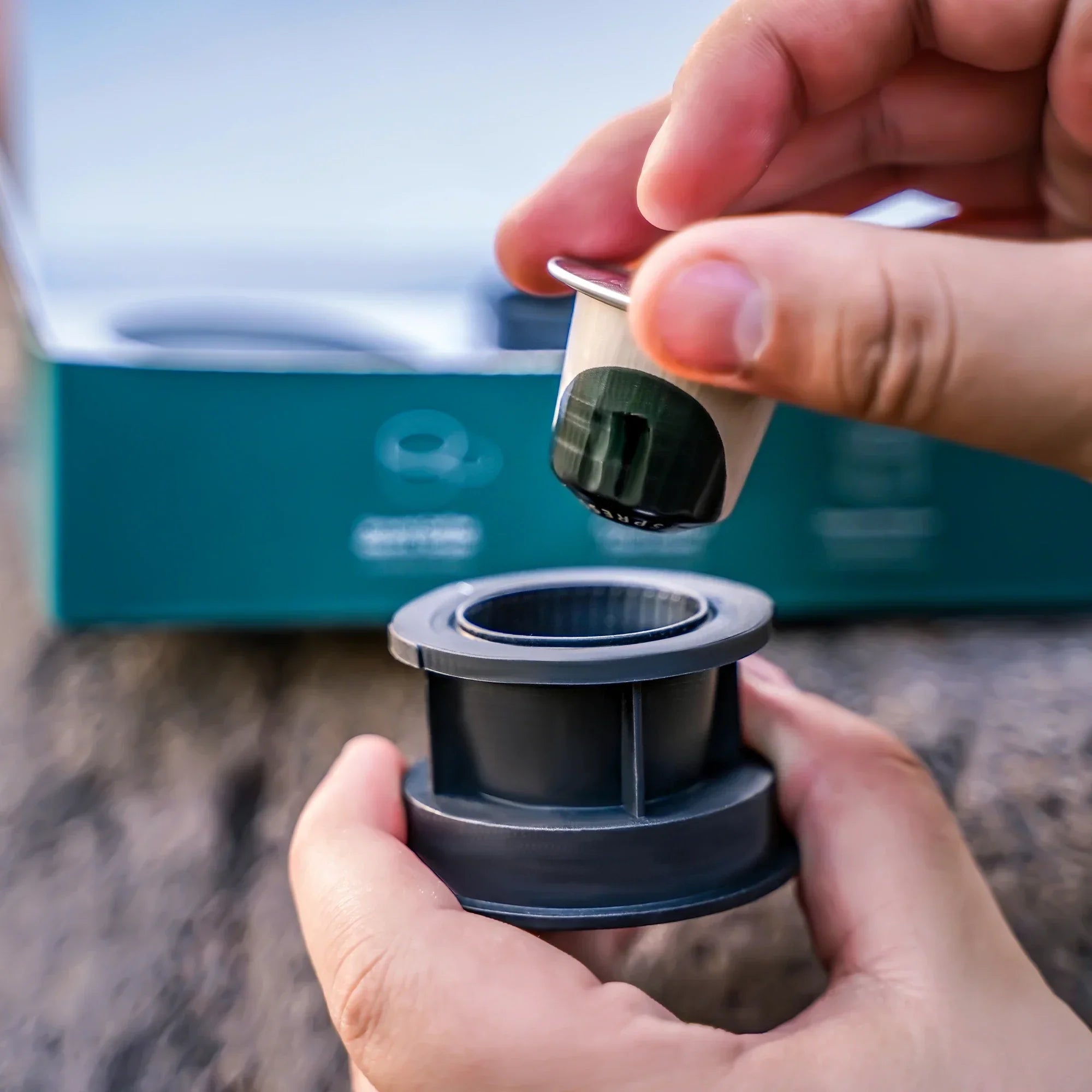 Person inserting Nespresso Original capsule into dark gray OutIn Nano capsule adapter.