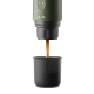 Forest green OutIn Nano portable espresso machine brewing rich espresso with amber crema into a dark grey cup.