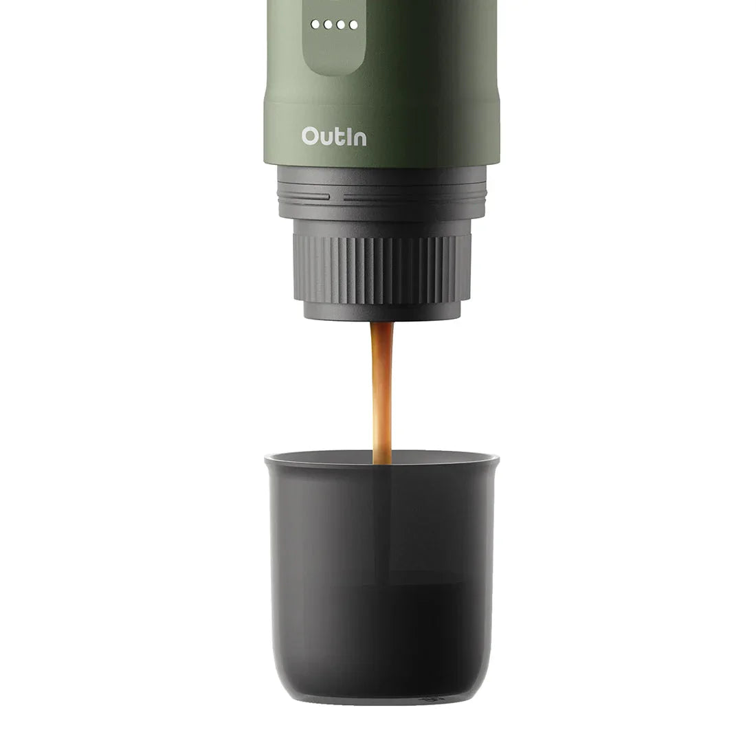 Forest green OutIn Nano portable espresso machine brewing rich espresso with amber crema into a dark grey cup.