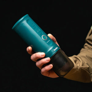 OutIn teal nano portable espresso machine held in hand, showcasing its sleek design and portability.